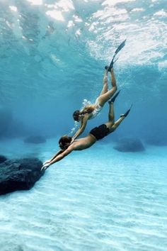 two people are swimming in the water with their feet up and holding onto paddles