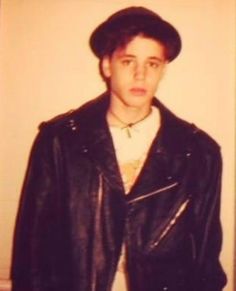 a young man wearing a leather jacket and hat