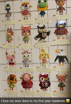 a bunch of little cartoon characters hanging on a white brick wall next to each other