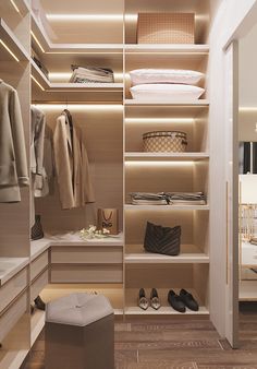 a walk in closet with clothes and shoes on the shelves next to an open door