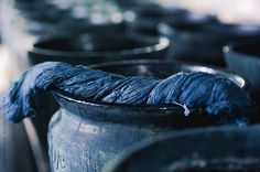 blue yarn is sitting on top of an old metal pot with other pots in the background