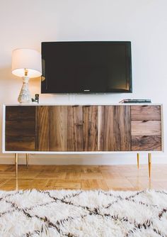 a tv on top of a wooden cabinet in a room with white walls and wood flooring