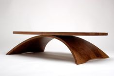 a wooden table with curved legs on a white background in the shape of an arch