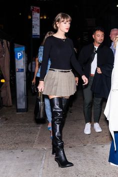 a woman walking down the street in black boots