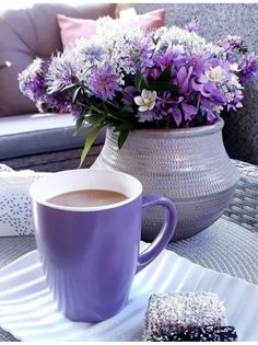 a cup of coffee sitting on top of a table next to a vase filled with flowers