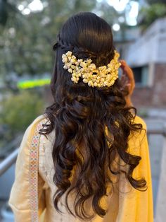 a woman with long dark hair wearing a yellow dress and a flowered headpiece