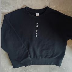 Upgrade your everyday sweatshirt with this premium crew neck in Black. Designed with a casual, yet elevated look. Created with intention and with the highest quality fabrics. Each sweatshirt has an affirmation printed on the inside tag for positive vibes all day. Wear as a daily reminder of what a strong mother you are. Fit: Sweatshirt is designed to have a shorter, more boxy fit (not cropped) Model is 5'1" and wearing a size Small Features: "Mother" printed down the front in white Color: Black Black Relaxed Fit Comfortable Sweater, Black Comfortable Relaxed Fit Sweater, Trendy Crew Sweatshirt For Layering, Black Crew Neck Sweatshirt With Text Print, Trendy Everyday Crew Neck Sweatshirt, Trendy Crew Neck Sweats For Everyday, Athleisure Crew Neck Sweatshirt With Text Print, Black Slogan Sweatshirt Crew Neck, Relaxed Fit Graphic Print Sweatshirt