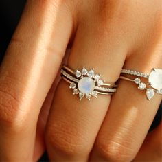 a woman's hand with two rings on it and an opal stone in the middle