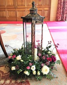 a lantern with flowers and greenery on the floor