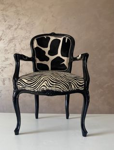 a zebra print chair sitting in front of a wall with an animal print upholstered back