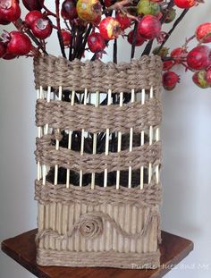 a basket with sticks sticking out of it sitting on top of a wooden table next to a vase filled with flowers