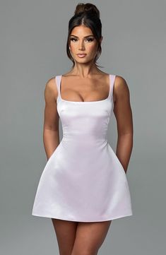 a woman in a short white dress posing for the camera with her hands on her hips