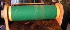 a roll of green fabric sitting on top of a wooden table