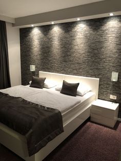 a large bed sitting in a bedroom next to a wall with lights on top of it