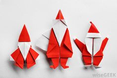 three origami santa clauss, one red and one white on a white background