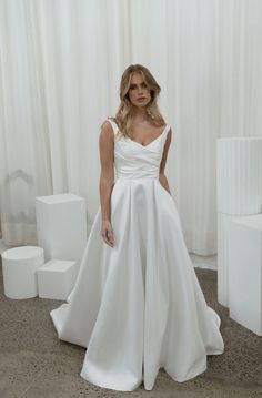 a woman in a white wedding dress standing next to some blocks and boxes on the floor