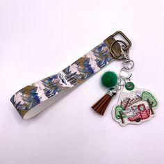 a pair of scissors and keychain on a white surface with a green pom - pom