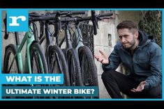 a man sitting on the ground next to some bikes and pointing at something in front of him