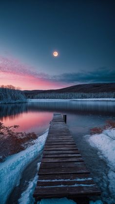 a wooden dock sitting on top of a lake under a moon filled sky with clouds