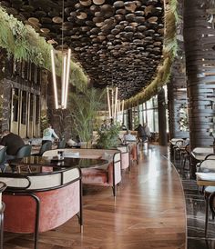 the interior of a restaurant with tables and chairs, plants hanging from the ceiling above