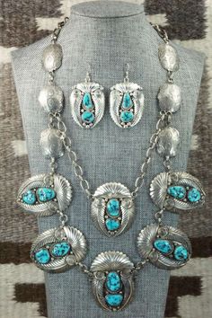 This vintage turquoise and sterling silver necklace and earrings set was made by Navajo silversmith Nora Tsosie. The back of the necklace is signed NT and stamped sterling. Please note this is a pre-owned piece, with patina, in vintage condition.Necklace: 28"Length: 2 1/8"Width: 1 3/4"Earrings:Length: 2 1/4"Width: 1 1/4"Free shipping on all orders! We ship with USPS and always include tracking. All orders ship within a day of payment.Returns are accepted up to 30 days after you receive your orde Elegant Turquoise Concho Jewelry, Elegant Blue Concho Jewelry, Elegant Blue Jewelry With Concho Detail, Sterling Silver Turquoise Concho Jewelry, Artisan Jewelry With Matching Earrings For Collectors, Southwestern Silver Jewelry With Inlay, Artisan Collectible Jewelry With Matching Earrings, Turquoise Concho Jewelry For Gifts, Concho Sterling Silver Necklace For Gifts