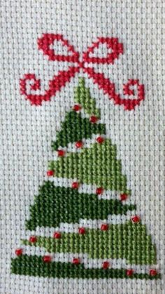 a cross stitch christmas tree with red ribbon