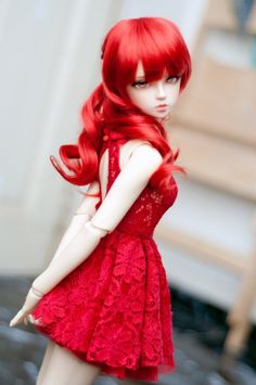 a doll with long red hair wearing a red dress