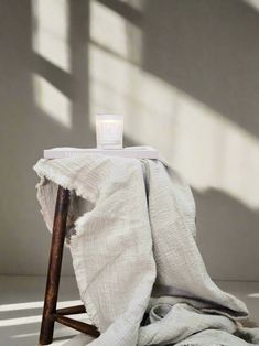 a white blanket sitting on top of a wooden chair next to a bottle of water