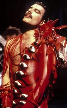 a man dressed in red and silver with spikes on his chest