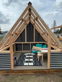 a small house with a roof made out of metal pipes and wooden beams, sitting in the grass