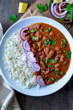 a white plate topped with rice and beans next to a bowl filled with red onions