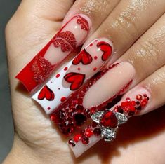 a woman's hand with red and white nail polishes on her nails, decorated with hearts