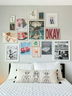 a white bed topped with lots of pictures on the wall