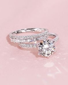 two wedding rings on top of each other, one with a diamond in the middle