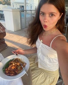 a woman holding a fork and knife in front of a plate of food