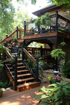 a wooden deck with stairs leading up to the top floor and plants on either side