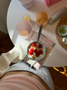 a person sitting at a table with a bowl of cereal and fruit on top of it