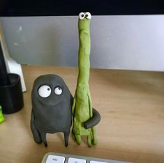 a computer keyboard sitting on top of a wooden desk next to a fake green creature