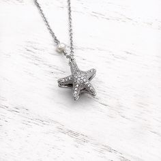 Dive into whimsical elegance with our Starfish Hidden Pearl Necklace—a playful yet refined masterpiece that captures the enchanting splendor of the starfish. This exquisite necklace unveils a hidden pearl within the intricacies of the starfish design, adding a touch of mystery to its charm. Whether worn for a special occasion or to elevate your everyday style, this piece is a testament to seaside allure. Bring the magic of the ocean to your ensemble and showcase your love for marine-inspired sop Elegant Starfish Charm Jewelry As Gift, Elegant Starfish Charm Jewelry Gift, Elegant Starfish Charm Jewelry For Gifts, Starfish-shaped Necklace With Pearl Charm For Gift, Elegant Starfish Necklace For Gift, Elegant Starfish Charm Pendant Jewelry, Silver Pearl Jewelry With Star Charm, Elegant Pendant With Starfish Charm, Elegant Jewelry With Starfish Charm