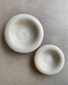 two white bowls sitting next to each other on top of a gray tablecloth covered floor