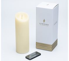 a lit candle next to a box and remote control