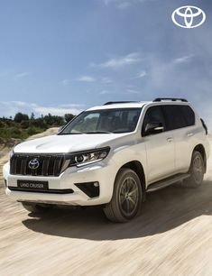 the new toyota land cruiser is driving on a dirt road with trees in the background