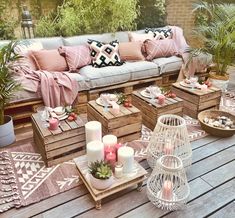 an outdoor patio with wooden pallets, candles and pillows on the table in front of it