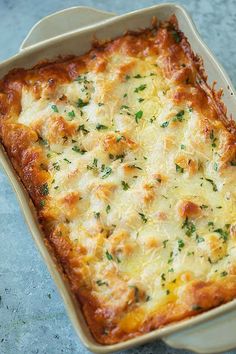 a casserole dish with cheese and parsley in it on a blue surface