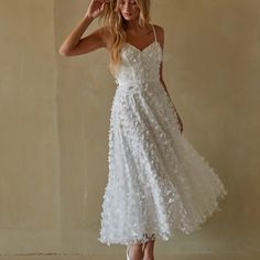 a woman in a white dress is posing for the camera with her hand on her head