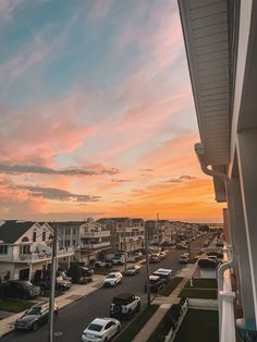 cars parked on the street in front of some houses at sunset or sunrise time,