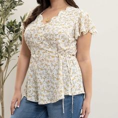 An Ivory Peplum Style Floral Top Featuring Flutter Sleeves, Scalloped Surplice Neckline Detail And Tie At Waist. Feminine Yellow V-neck Blouse, Cream Floral Print Flowy Tops, Flowy Yellow Blouse For Brunch, Yellow Flowy Short Sleeve Top, Flowy Yellow Short Sleeve Blouse, Feminine Yellow Blouse For Brunch, Peplum Styling, Cream Yellow, Surplice Neckline