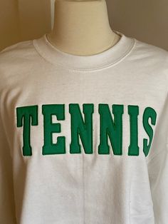 Show the world how much you love tennis by wearing this comfortable crewneck sweatshirt. Heavy weight cotton/poly blend white color crewneck sweatshirt with hot pink appliqué embroidery.  Also available at,  Painted Tree in Ballwin, Missouri Cheap Screen Print Tennis Tops, Collegiate White Sweatshirt With Screen Print, White Collegiate Sweatshirt With Screen Print, White Collegiate Style Sweatshirt With Screen Print, Sporty T-shirt With Embroidered Text For College, Cotton Sweatshirt With Screen Print For Sports Season, Sporty Long Sleeve T-shirt With Letter Embroidery, Sporty Crew Neck Sweatshirt With Embroidered Logo, White Crew Neck Sweatshirt With Letter Embroidery