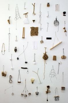 a white wall covered in lots of different types of jewelry hanging from hooks and strings