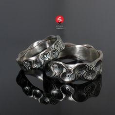 two silver rings sitting on top of a black surface with the words,'love is in